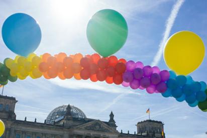 Eine Kette aus Luftballons in den Farben des Regenbogens vor dem Reichstagsgebäude